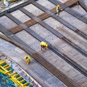 Werknemers aan het werk met metalen structuren op een bouwplaats, benadrukkend de toepassing van brandwerende coatings voor veiligheid en duurzaamheid.