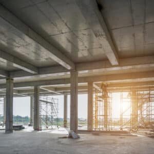 Lege bouwlocatie met zicht op betonnen kolommen, steigers en natuurlijk licht, illustrerend de constructie van een gebouw voor brandwerende coating toepassingen.