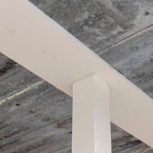 Brandwerende staalconstructie met een witte coating, zichtbaar op een betonnen plafond.